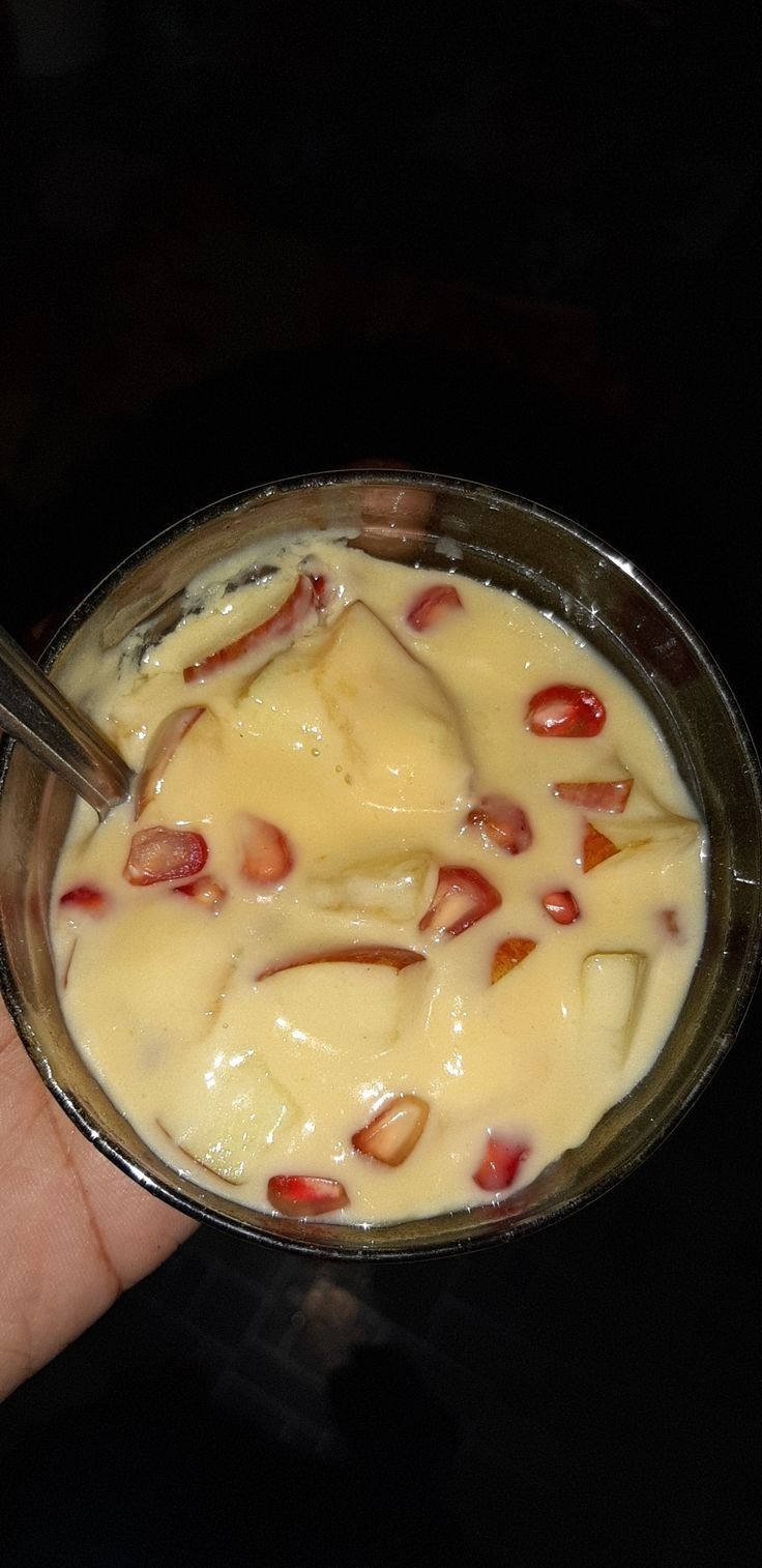 a person is holding a spoon in a bowl of food with cheese and almonds