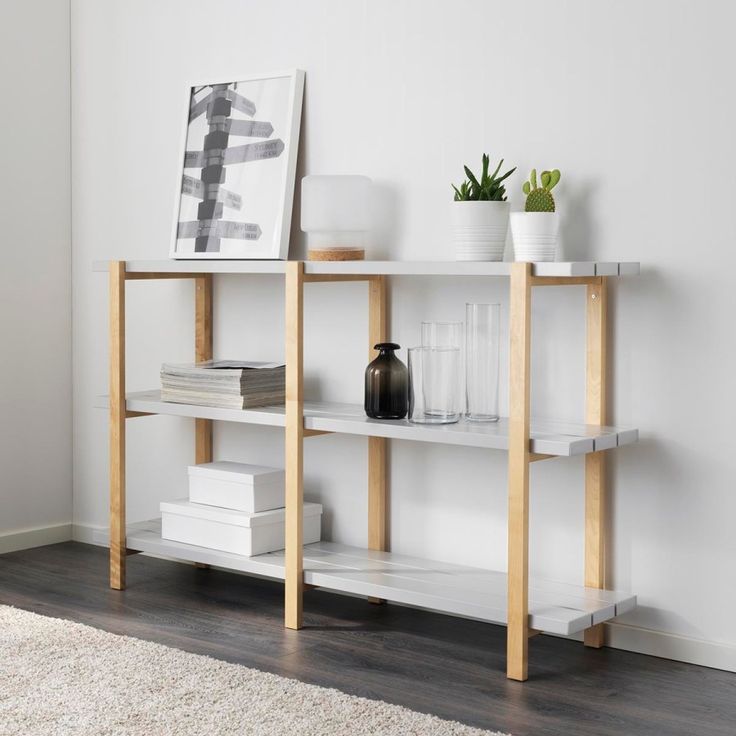 a white shelf with books and plants on it next to a wall mounted art piece