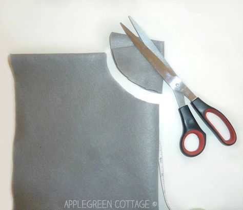 a pair of scissors sitting on top of a piece of gray fabric next to a pair of red handled scissors