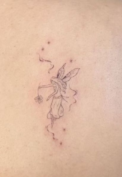 a small fairy tattoo on the back of a woman's left shoulder and chest