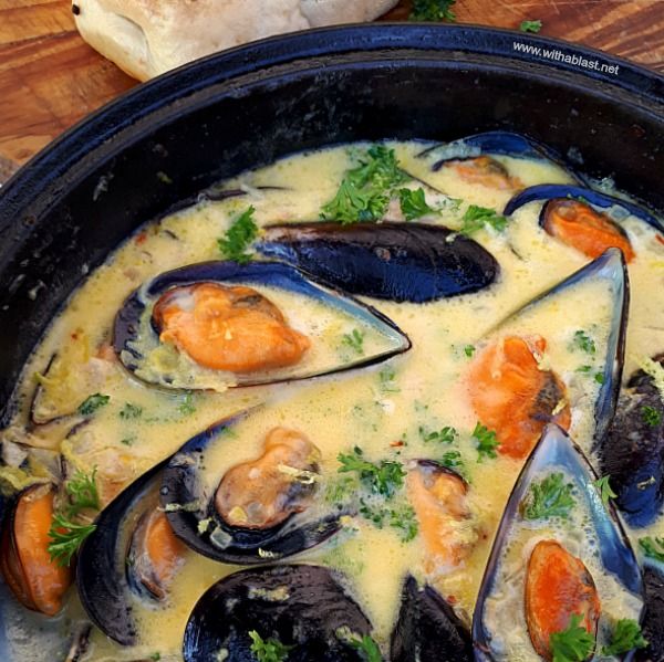 a pan filled with mussels and sauce on top of a table