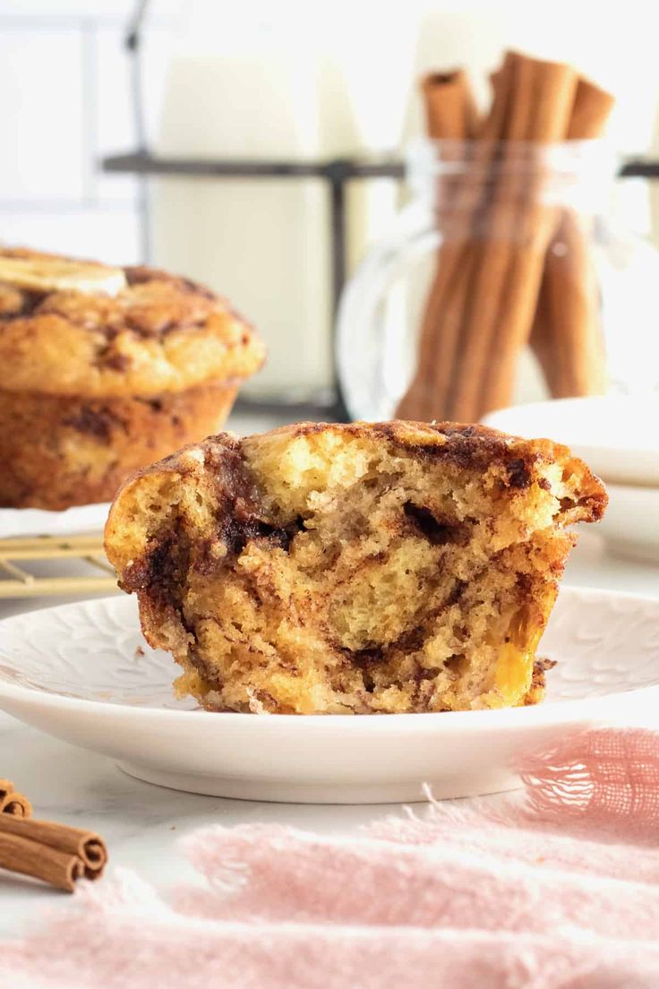 a close up of a muffin on a plate with cinnamon sticks in the background