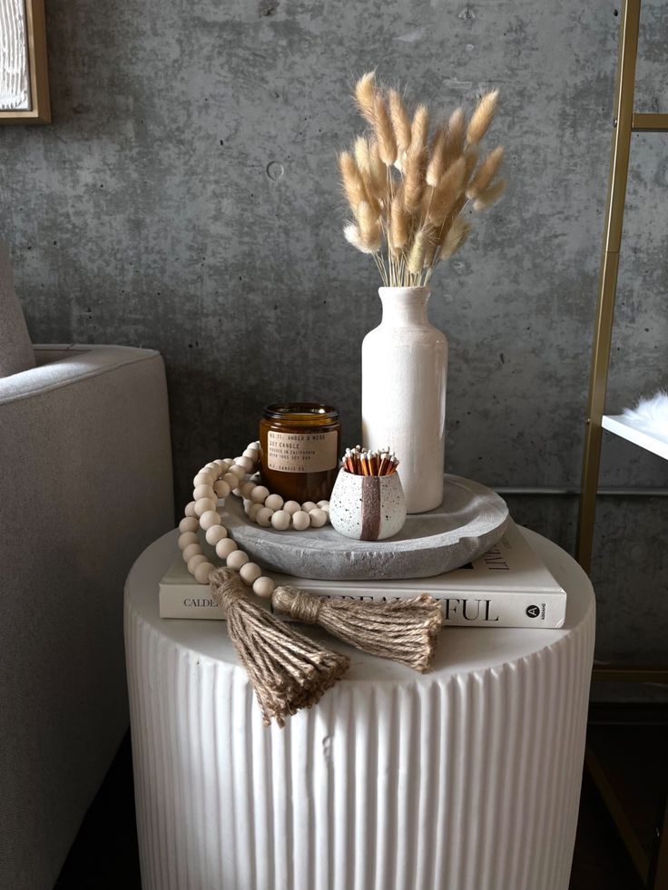 a white vase sitting on top of a table next to a candle and some beads