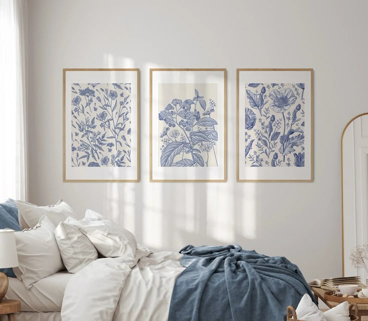 a bedroom with white walls and blue floral prints on the wall