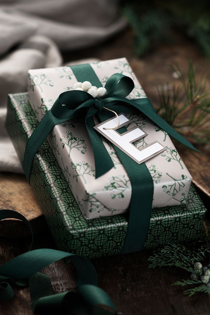 a present wrapped in green and white paper with a ribbon tied around it on top of a wooden table