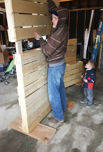 a man standing next to a little boy in a room filled with wooden pallets