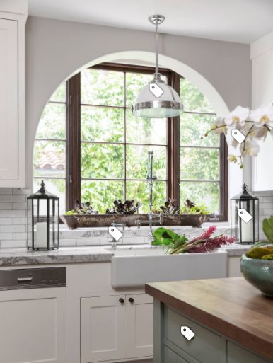 a kitchen with white cabinets and an arched window