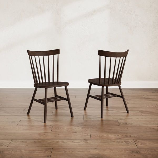 two wooden chairs sitting side by side on a hard wood floor in front of a white wall