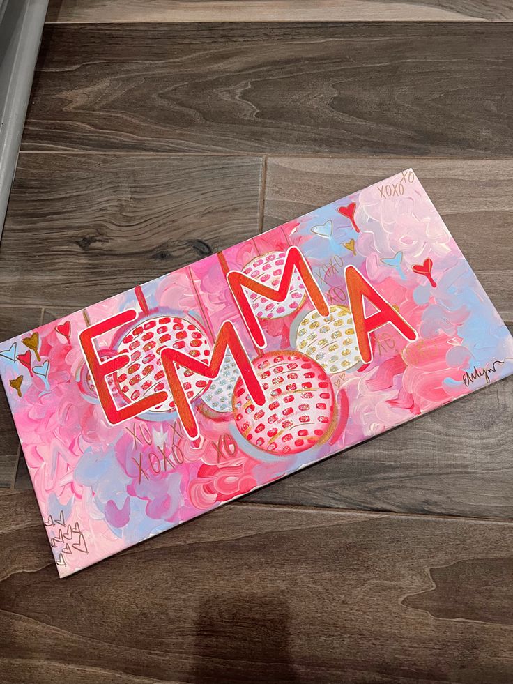 a piece of paper with the word ema on it sitting on top of a wooden floor