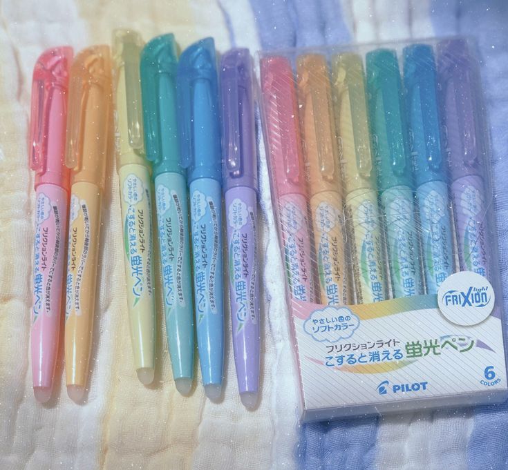 five different colored pens are lined up in a row on a towel with japanese writing