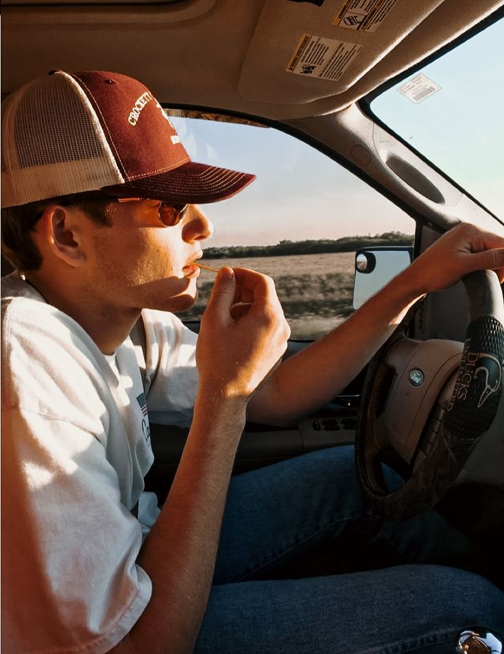 a man sitting in the driver's seat of a car with his hand on the steering wheel