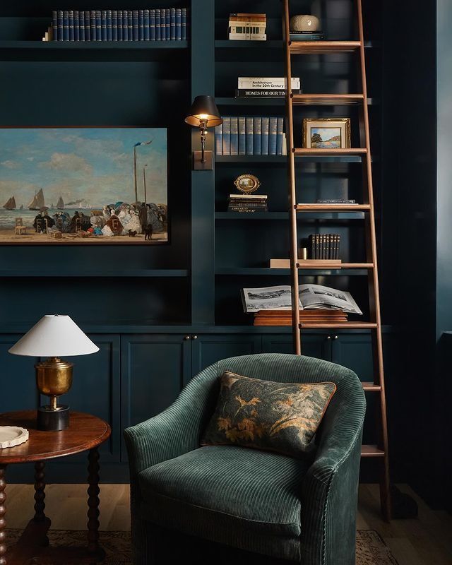 a living room filled with furniture and bookshelves next to a painting on the wall