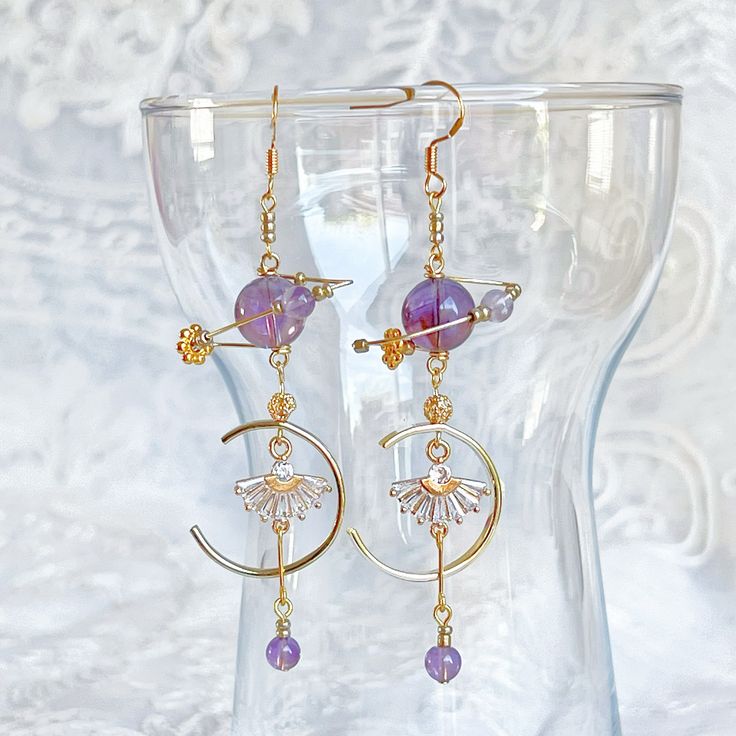 Amethyst Planet and Fan Earrings These beautiful Amethyst Planet and Fan Earrings will bring a celestial sparkle to any look. Crafted from genuine amethyst stone, the earrings feature an abstract planet design, delicately decorated with a fan-like shape for a truly unique flair. Perfect for any special occasion. As a gift shop, we offer a complimentary gift box for every order. Detail: Length of one earring - 80mm; size of beads - 5-10mm Material: ear wire - sterling silver; beads - natural Amethyst;  Note: the Amethyst Planet and Fan Earrings are handmade locally in the UK, each pieces would vary slightly in detail.  About postage: Standard postage When choosing standard postage, we assume this order is for yourself, or you will wrap the item yourself before giving it out as a gift (the c Celestial Purple Dangle Earrings, Purple Celestial Dangle Earrings, Celestial Amethyst Gold Jewelry, Purple Adjustable Celestial Jewelry, Adjustable Purple Celestial Jewelry, Handmade Purple Celestial Earrings, Purple Amethyst Celestial Jewelry, Celestial Amethyst Purple Jewelry, Purple Round Spiritual Earrings