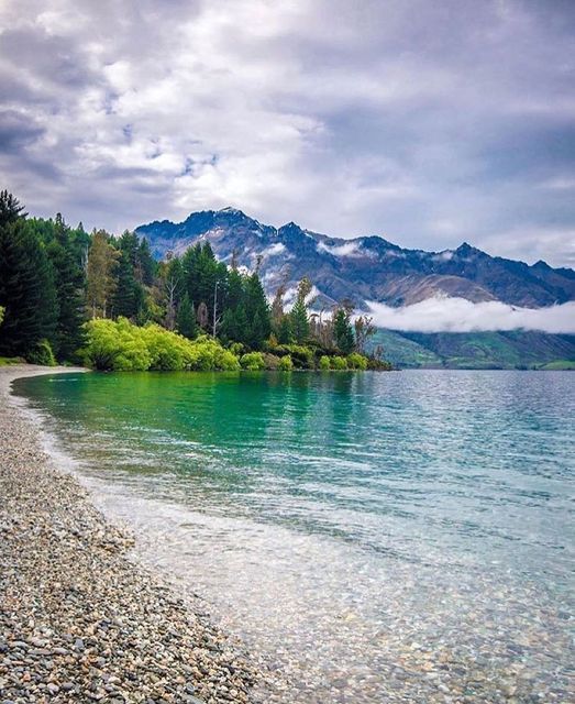 the water is crystal blue and green with mountains in the background