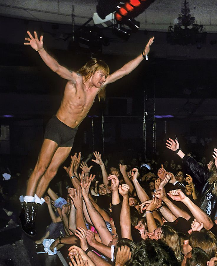 a shirtless man is in the middle of a crowd with his arms raised up