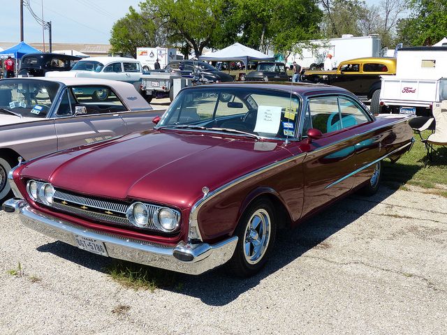 an old car parked in a parking lot next to other cars