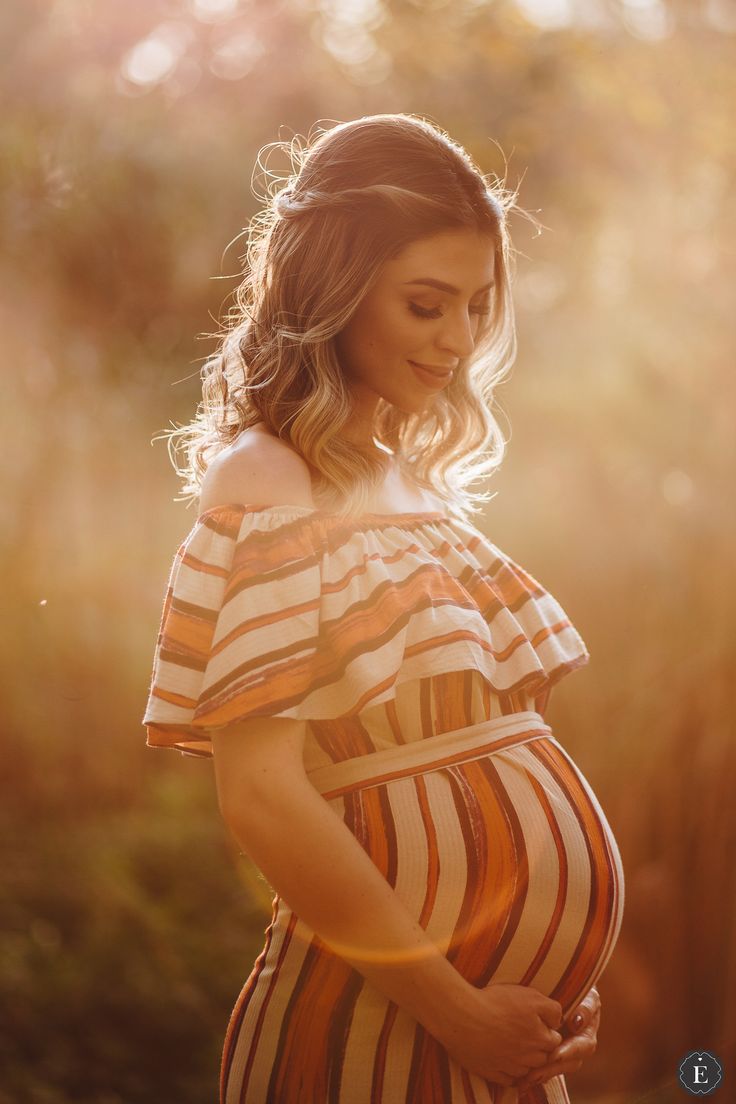 a pregnant woman is standing in the sunlight