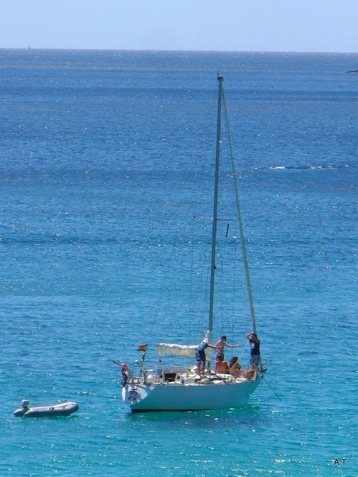 people on a sailboat in the middle of the ocean with another boat out to sea