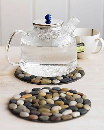 a glass tea pot and coaster on a table with rocks in front of it,