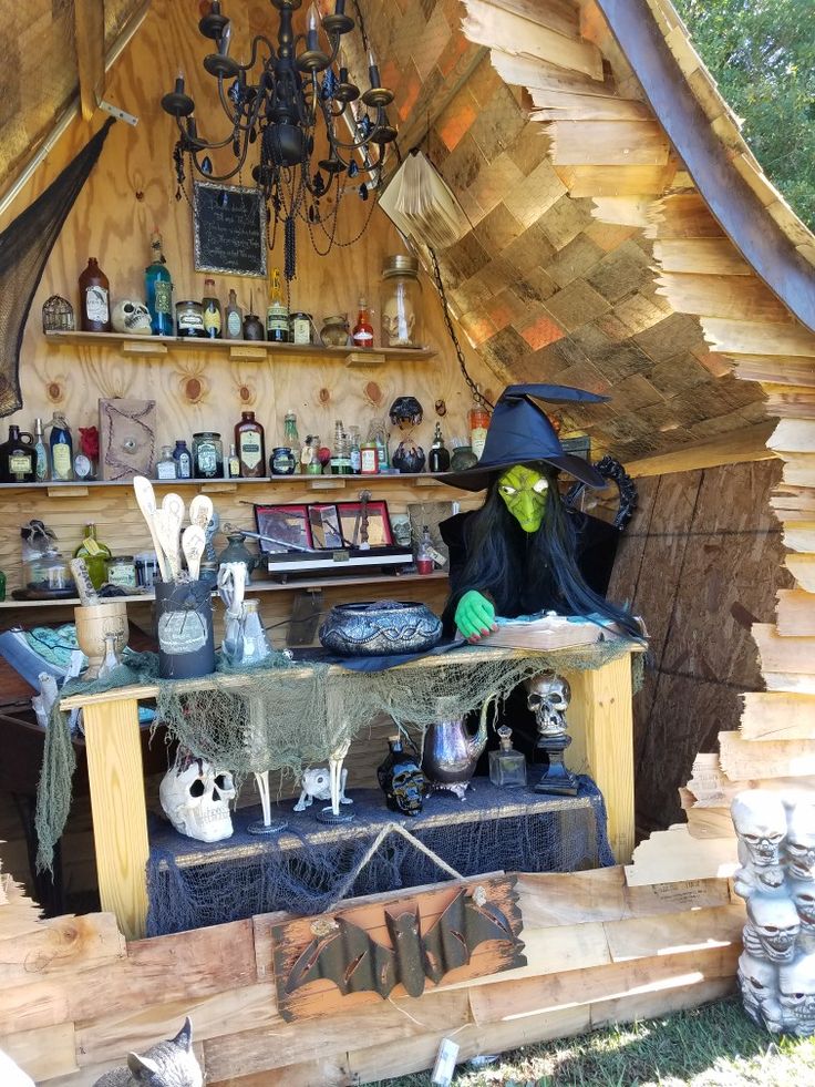 a wooden hut with halloween decorations on the outside and shelves full of items in it