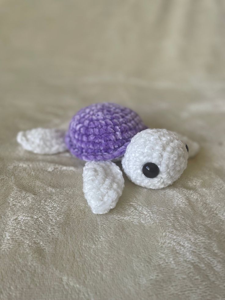 a crocheted turtle laying on top of a bed