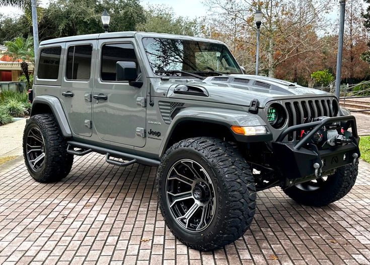 a gray jeep parked on top of a brick road