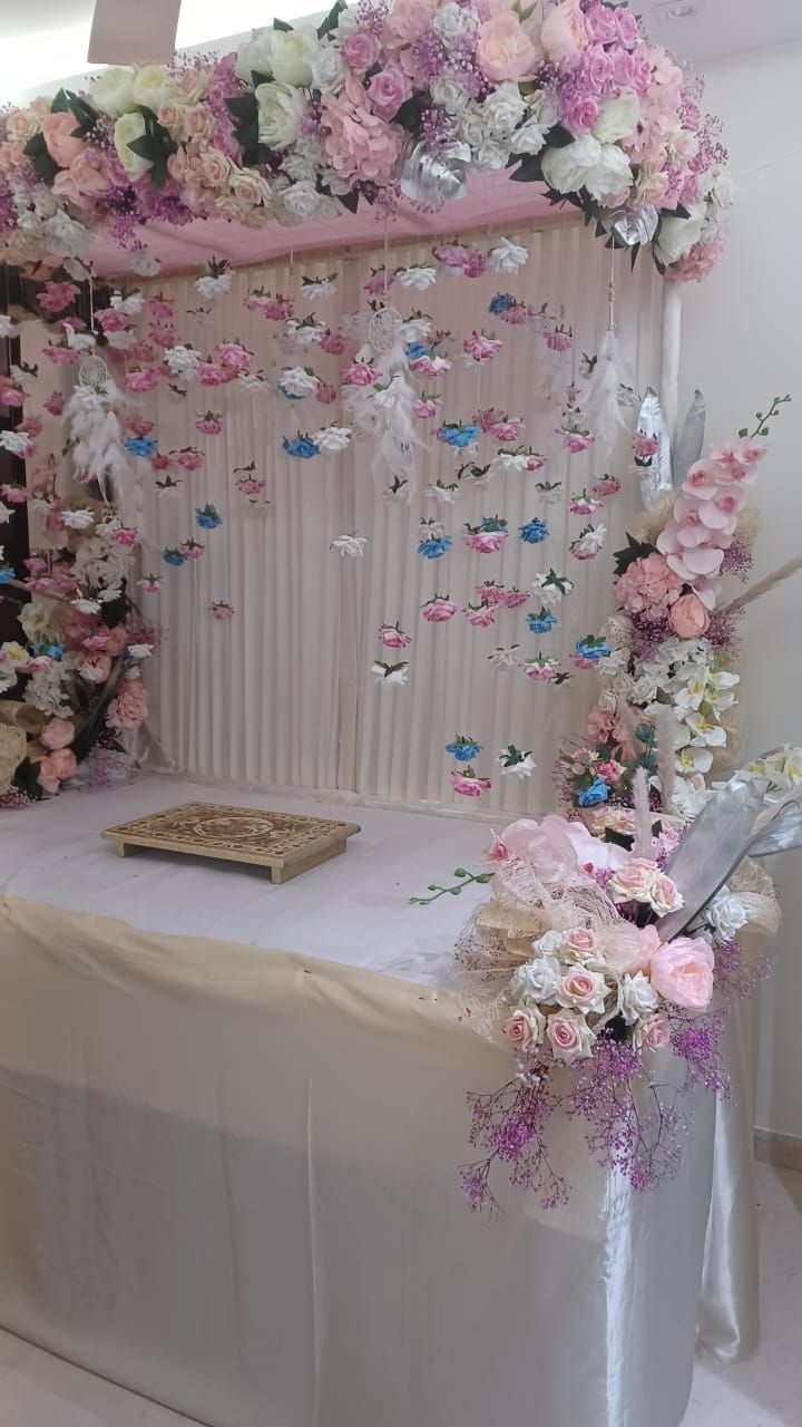 a white table topped with lots of pink and white flowers next to a wall hanging from the ceiling