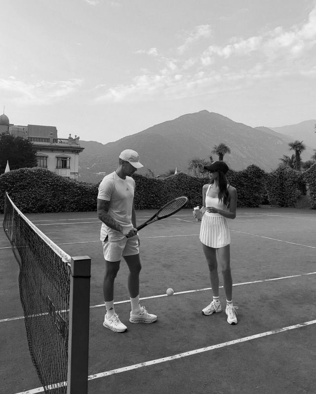 two people standing on a tennis court holding racquets and looking at each other