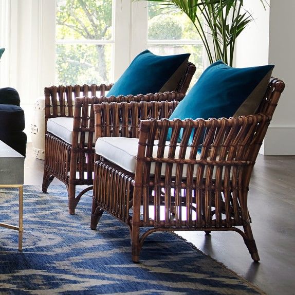 a living room with wicker furniture and blue pillows