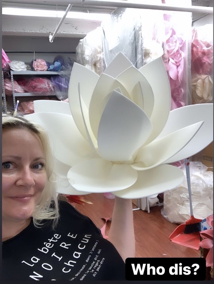 a woman holding up a large white paper flower