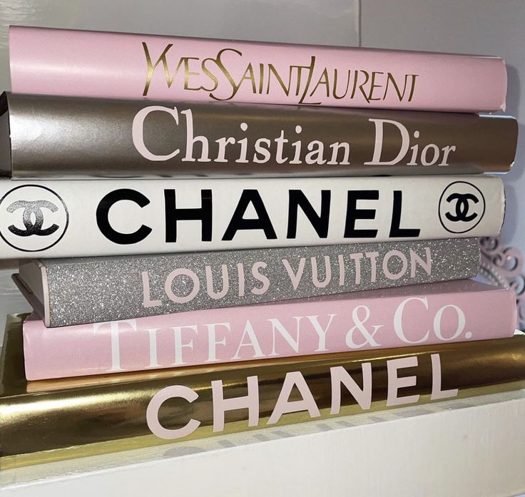 a stack of chanel books sitting on top of each other in front of a white wall