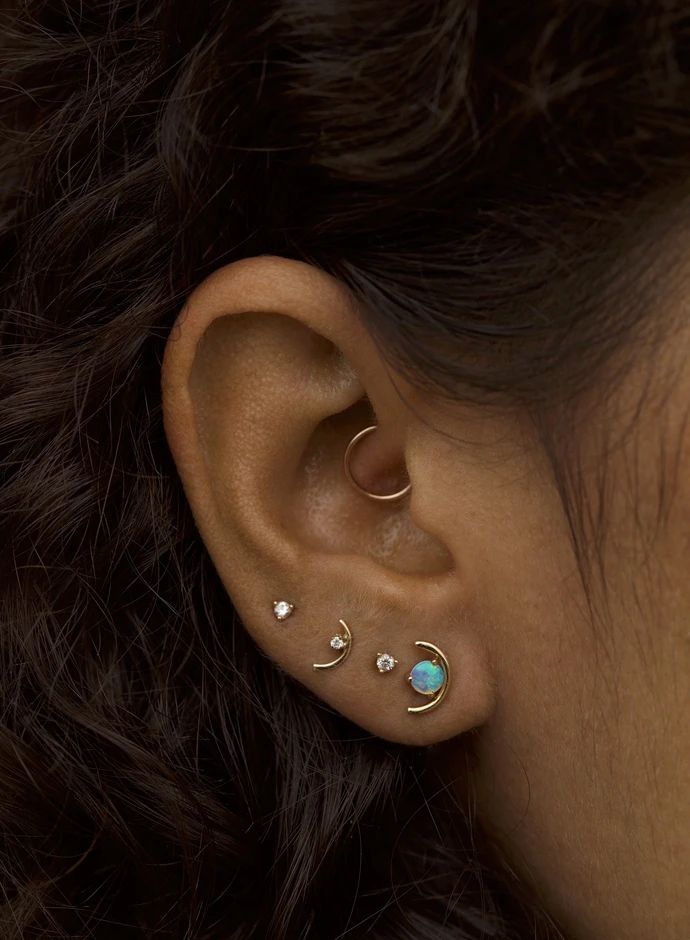 a woman's ear with three different colored stones in the shape of an ear