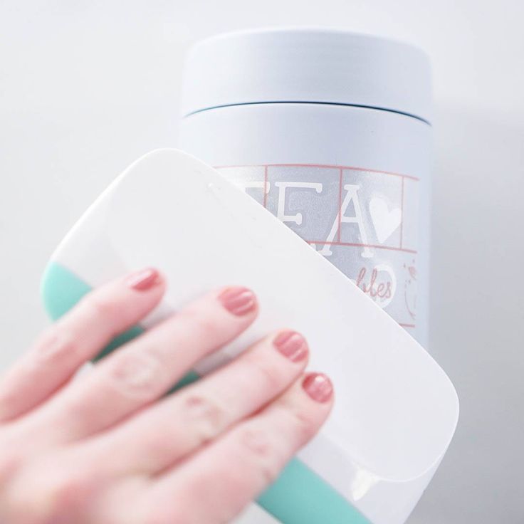 a woman's hand is holding a plastic container next to a white and blue cup