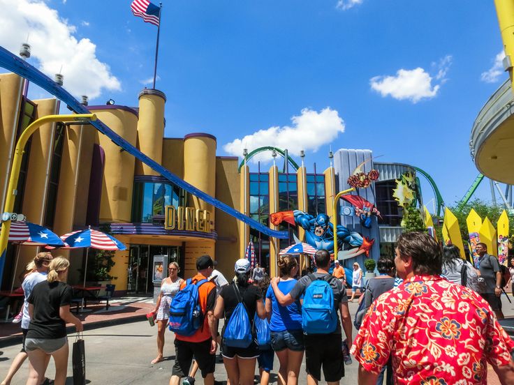 a group of people standing in front of a roller coaster at an amusement park or theme park