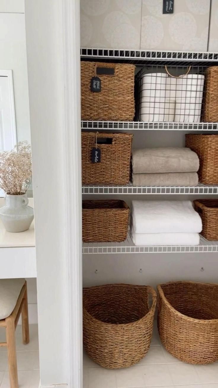 an organized closet with baskets and towels