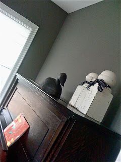 a black bird sitting on top of a dresser next to a box and a window