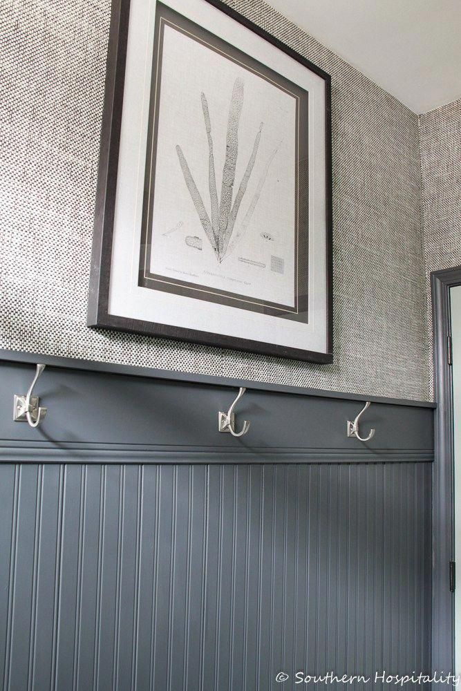 a bathroom with two hooks on the wall and a picture hanging above it's sink