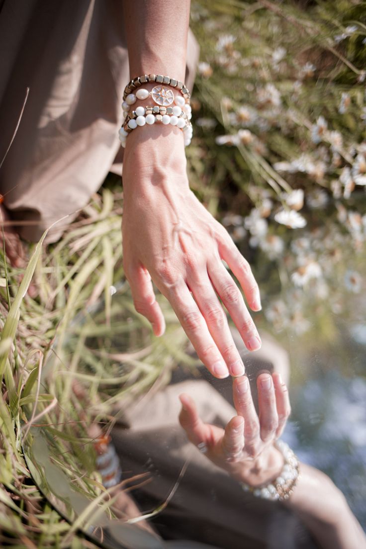 a woman's hand reaching for something in the grass with her other hand on top of it