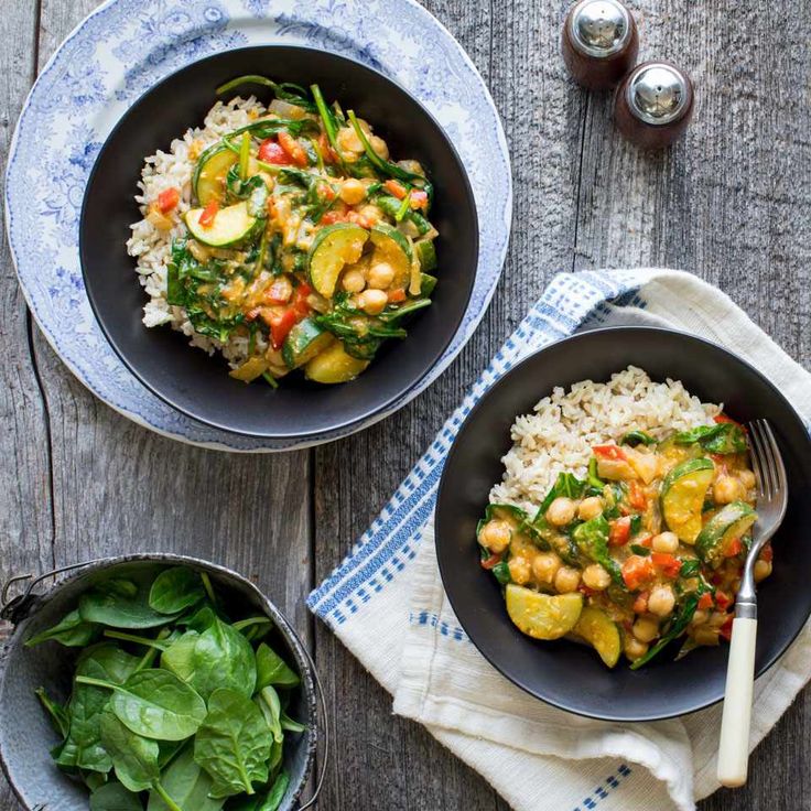 two bowls filled with rice and vegetables next to each other on top of a wooden table