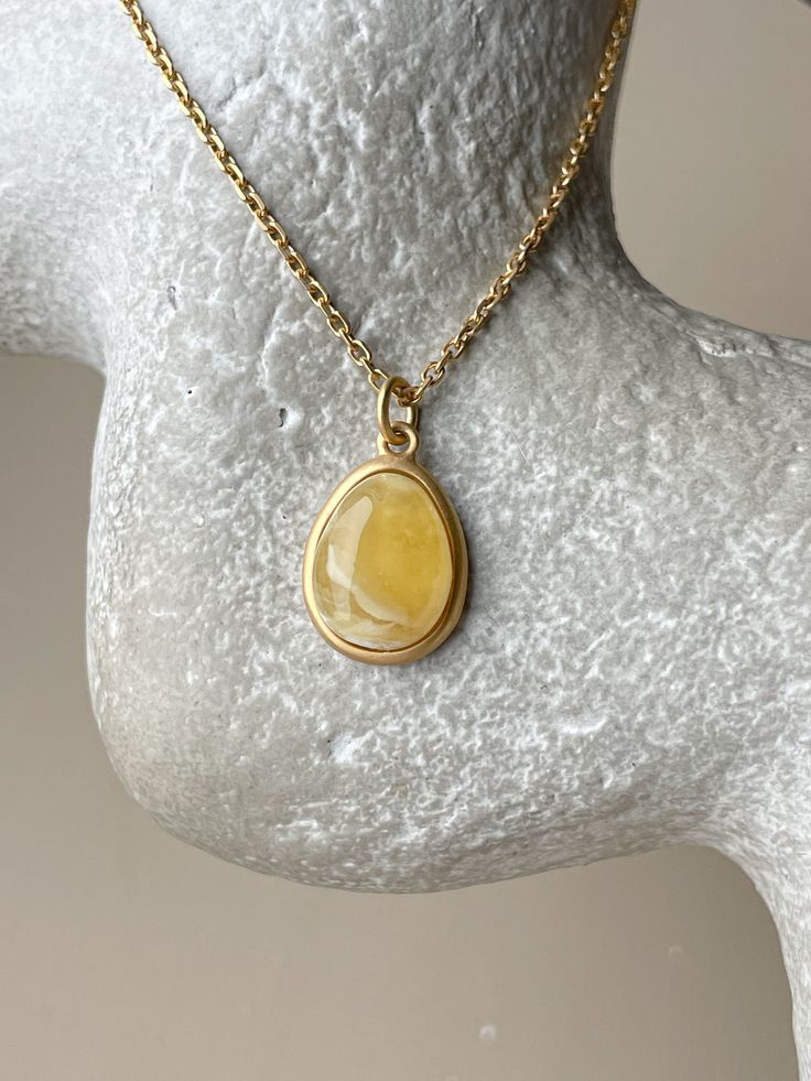 Embrace the captivating allure of the Baltic sea with this chic, elliptical amber pendant. Each piece showcases a pristine slice of natural Baltic amber, renowned for its warmth and depth, encased in a sophisticated gold-plated sterling silver frame. This pendant is the essence of elegance, designed to add a touch of timeless sophistication to any outfit. Its unique organic patterns ensure that no two pendants are alike, offering you an exclusive piece of the earth's beauty. This product is unique due to the stone and is presented as a single instance. Stone - 0.67" Size(US)- 18 Material - gold plated sterling silver and natural amber Modern Yellow Gold Jewelry With Oval Cabochon, Modern Yellow Gold Oval Cabochon Jewelry, Modern Gold Jewelry With Oval Cabochon, Luxury Amber Necklace With Polished Finish, Amber Pendant With Large Stone, Yellow Gold Cabochon Teardrop Pendant Necklace, Amber Pendant Necklace In Baltic Amber, Gold Cabochon Teardrop Pendant, Gold Cabochon Teardrop Pendant Jewelry