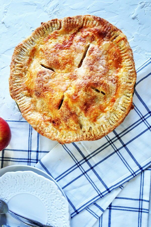 an apple pie sitting on top of a blue and white checkered table cloth with the title classic apple pie