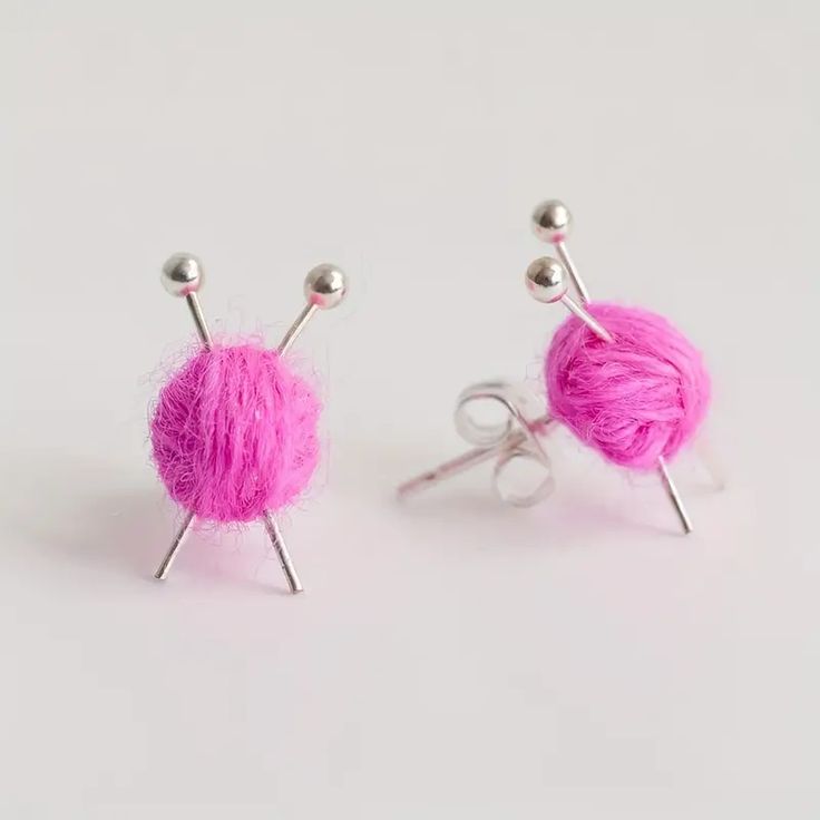 two pink balls of yarn with needles sticking out of them