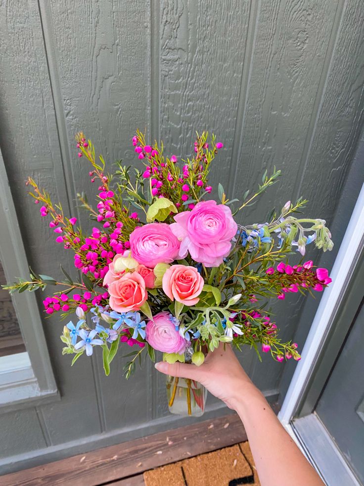 a person holding a bouquet of flowers in front of a door handle on a porch