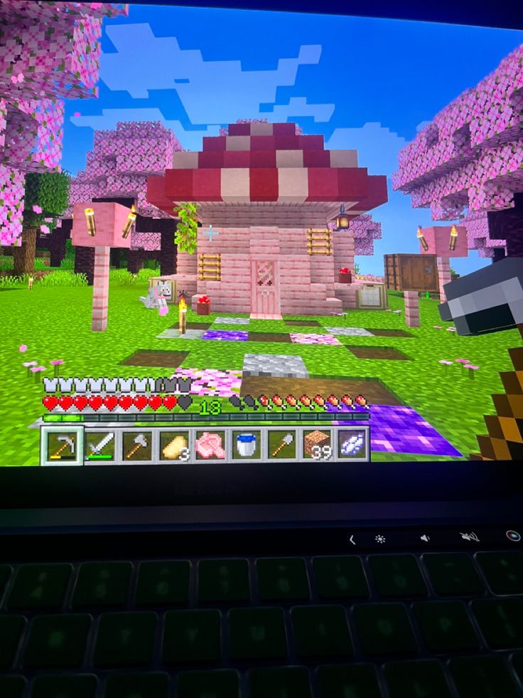 a laptop computer with a game on it's screen and the image of a mushroom house in the background