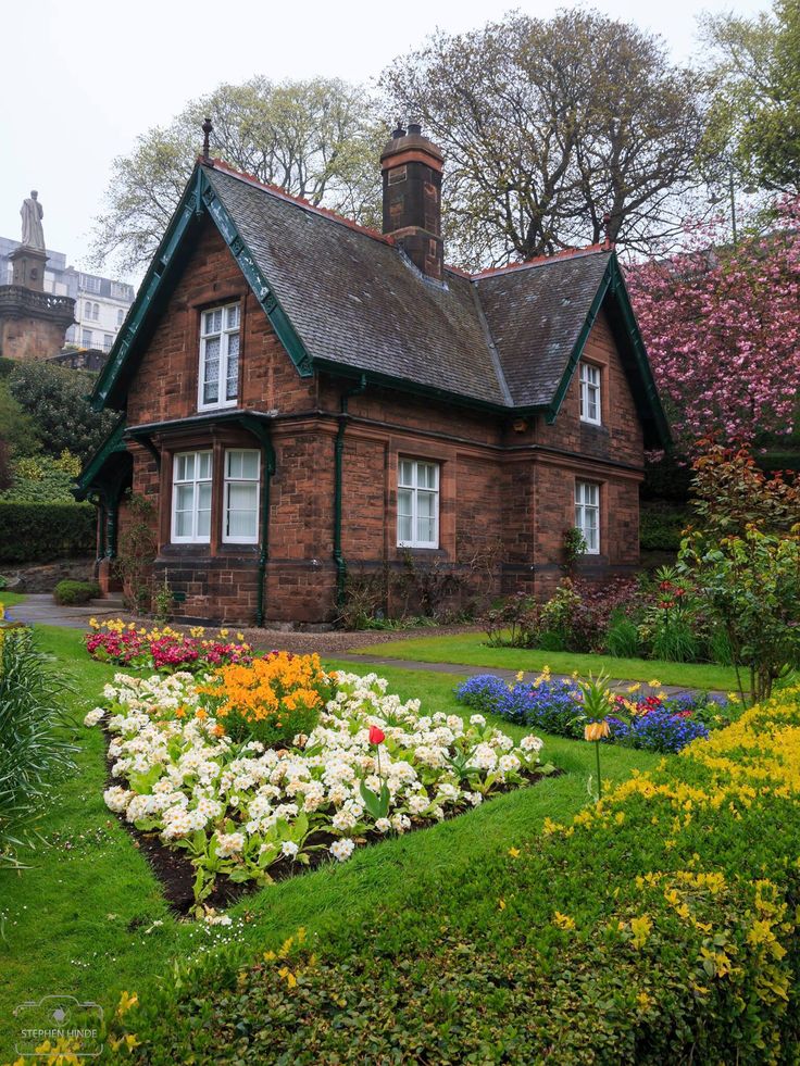 an old brick house surrounded by colorful flowers