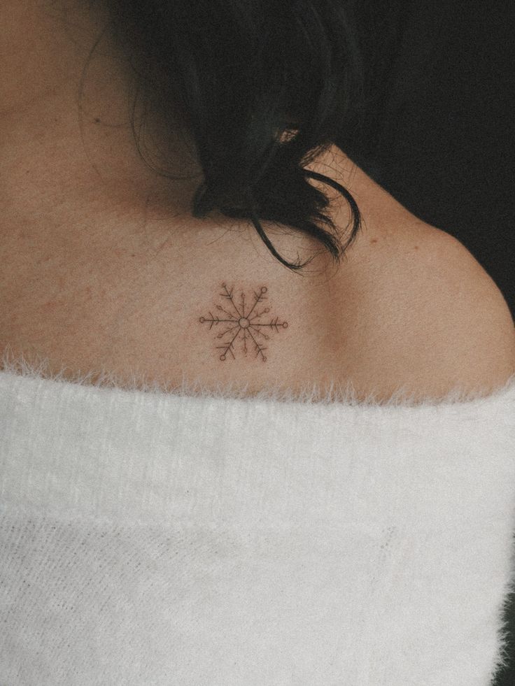 a woman with a small snowflake tattoo on her upper back shoulder and neck