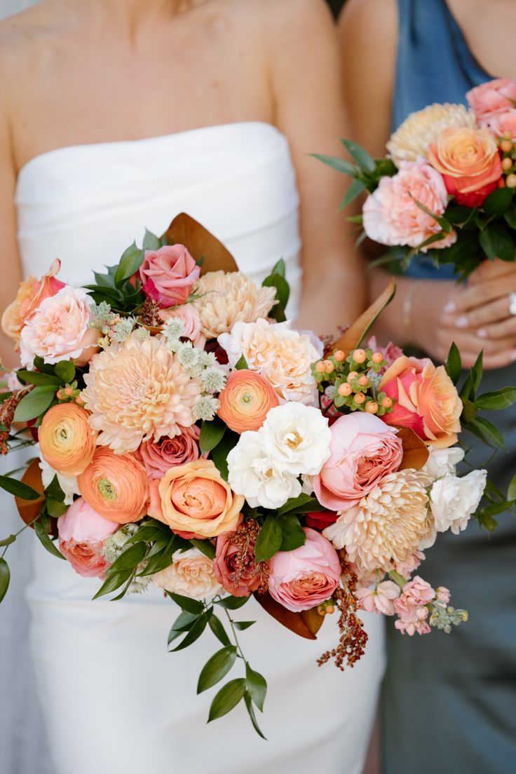 two bridesmaids holding bouquets of peach and white flowers in their hands,