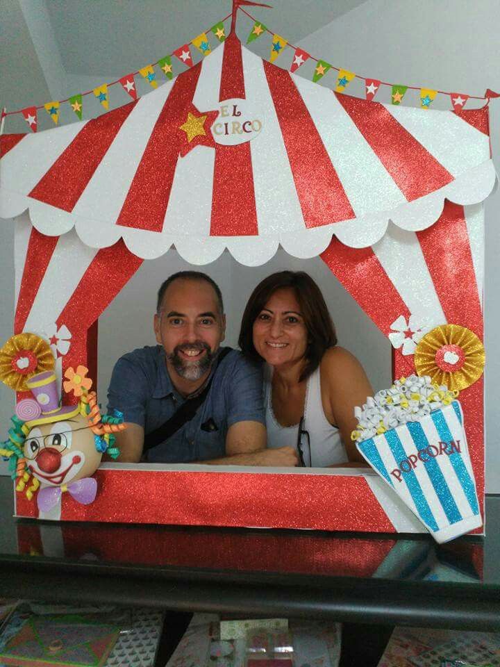 a man and woman sitting in front of a red and white circus tent with popcorn