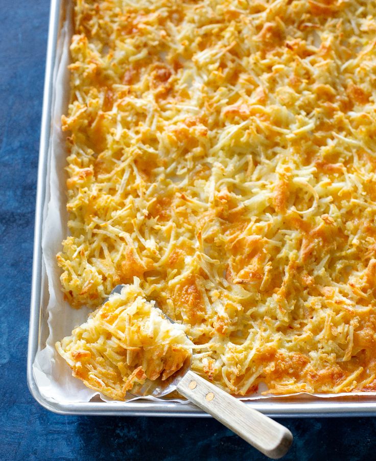 a casserole dish with cheese on top and a spatula next to it