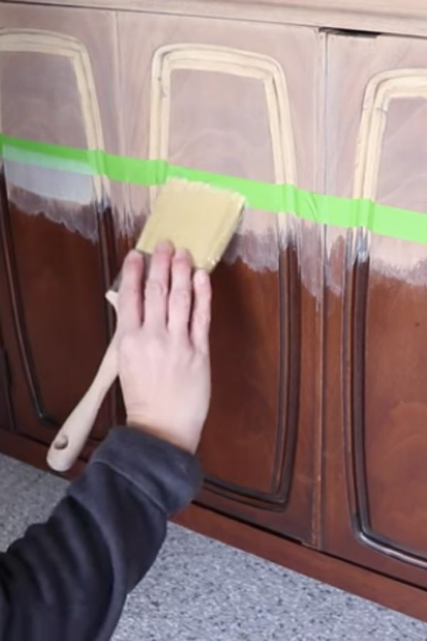 a person is using a sponge to paint the side of a cabinet